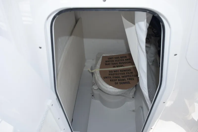 Slide: The Image of 2025 Sea Hunt Ultra 245 SE boat interior with compact marine toilet. - 17