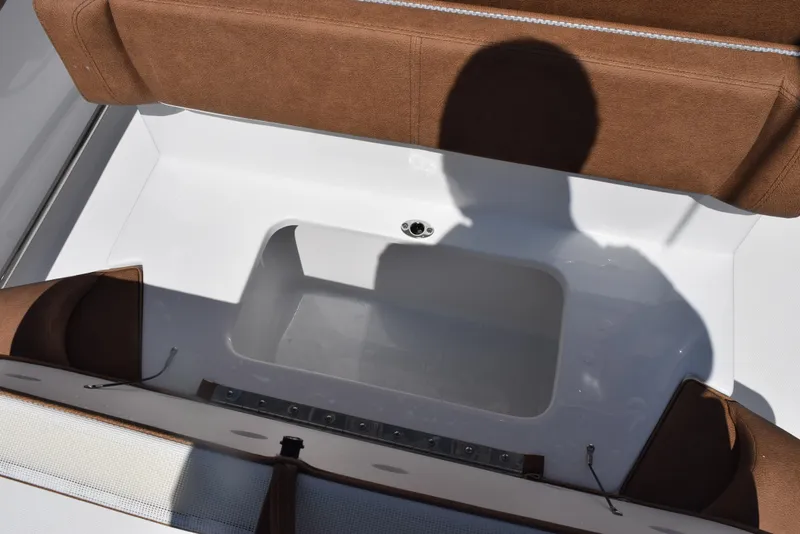 Slide: The Image of 2025 Sea Hunt Ultra 245 SE boat storage compartment with brown seating and shadow. - 19