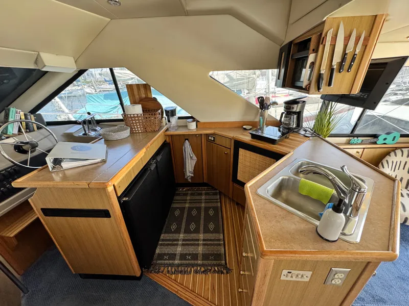 Slide: The Image of 2000 Bayliner 3988 yacht kitchen with sink, appliances, and wooden cabinetry. - 28