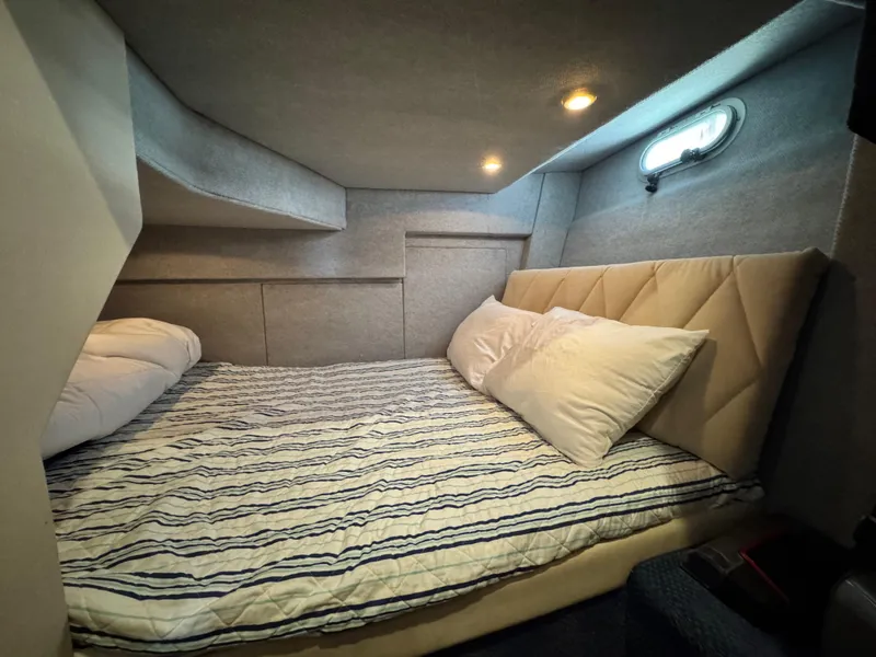 Slide: The Image of Cozy cabin interior of 2000 Bayliner 3988 with striped bedding and soft lighting. - 34