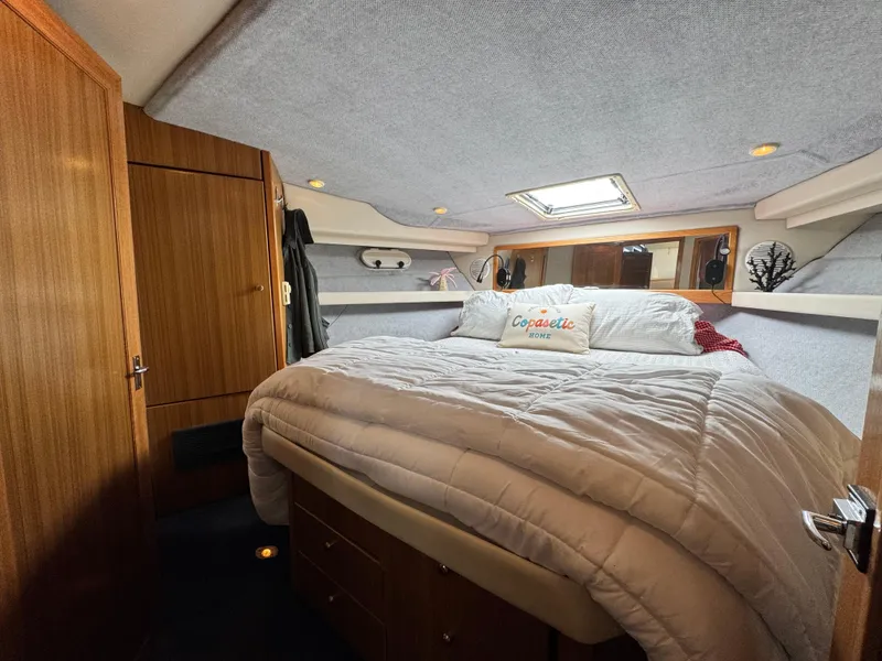 Slide: The Image of Cozy bedroom in 2000 Bayliner 3988 yacht with plush bedding and wooden cabinetry. - 39