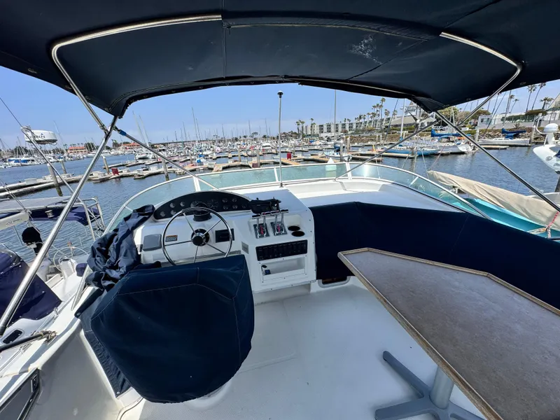 Slide: The Image of 2000 Bayliner 3988 yacht cockpit with marina view, featuring helm and seating area. - 47