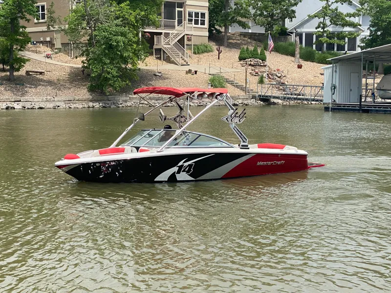Slide: The Image of 2011 MasterCraft X14 boat with red and black design on a lake. - 13