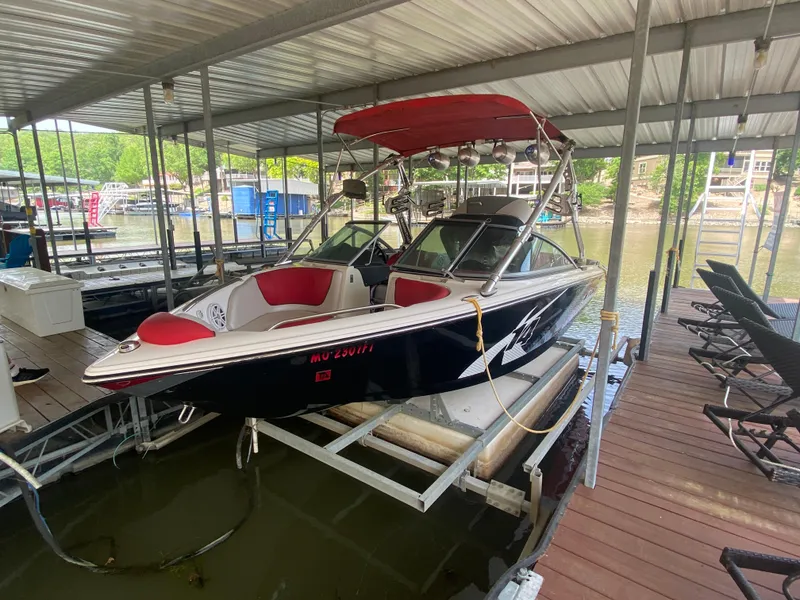 Slide: The Image of 2011 MasterCraft X14 boat docked under a covered marina with red and white seating. - 15