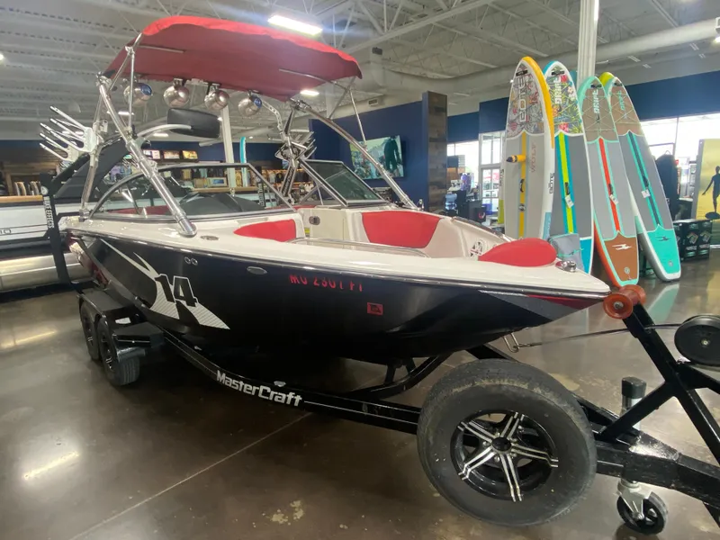 Slide: The Image of 2011 MasterCraft X14 boat with red interior and wakeboard tower, displayed indoors. - 19