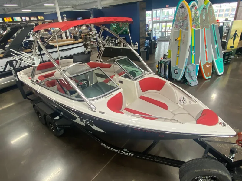 Slide: The Image of 2011 MasterCraft X14 boat with red and white interior, displayed indoors near paddleboards. - 20