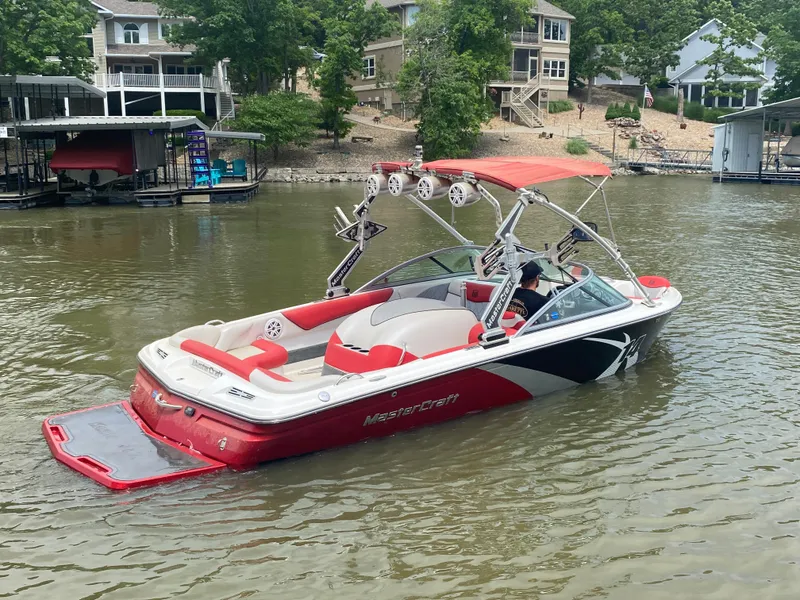 Slide: The Image of 2011 MasterCraft X14 boat on a lake, featuring red and white design with a wakeboard tower. - 6