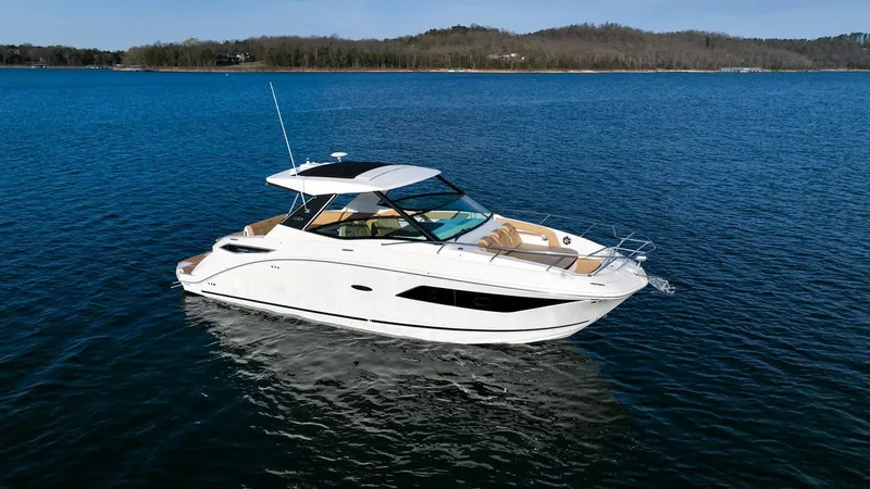 Slide: The Image of 2024 Sea Ray Sundancer 320 yacht on a serene lake with wooded shoreline. - 0