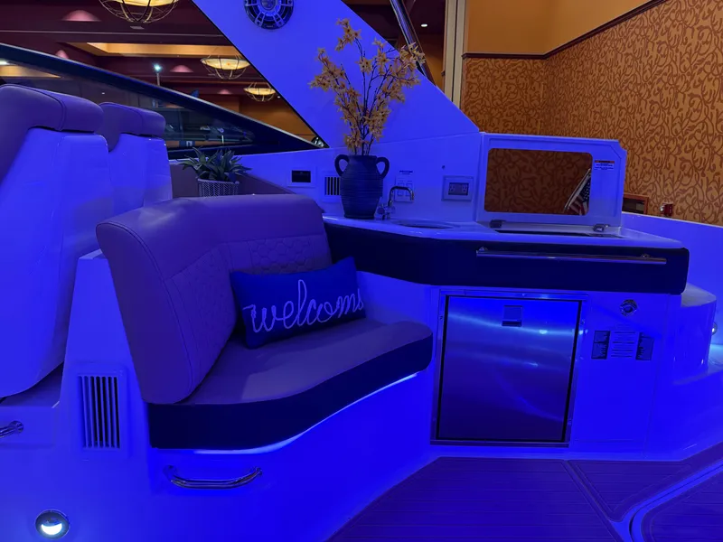 Slide: The Image of 2024 Sea Ray Sundancer 320 interior with blue lighting, featuring seating and kitchenette. - 7