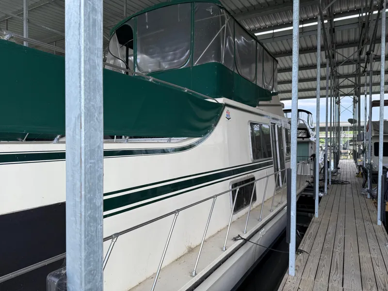 Slide: The Image of 1980 Harbor Master 47 docked in a covered marina, featuring green accents and upper deck enclosure. - 10