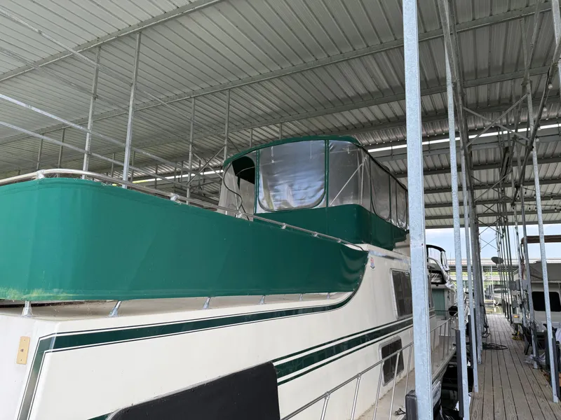Slide: The Image of 1980 Harbor Master 47 yacht with green canopy docked under a metal roof. - 9