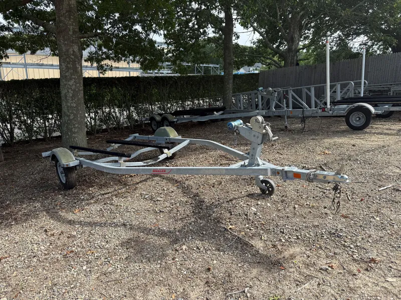 Slide: The Image of Empty boat trailer for 2016 Boston Whaler 150 Super Sport, parked on gravel under trees. - 10