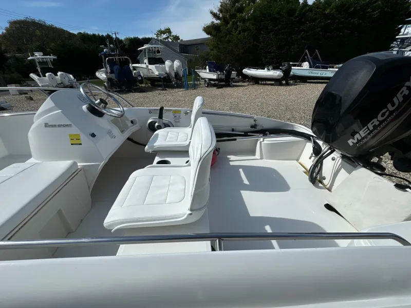 Slide: The Image of 2016 Boston Whaler 150 Super Sport boat with Mercury engine, white interior, parked outdoors. - 3