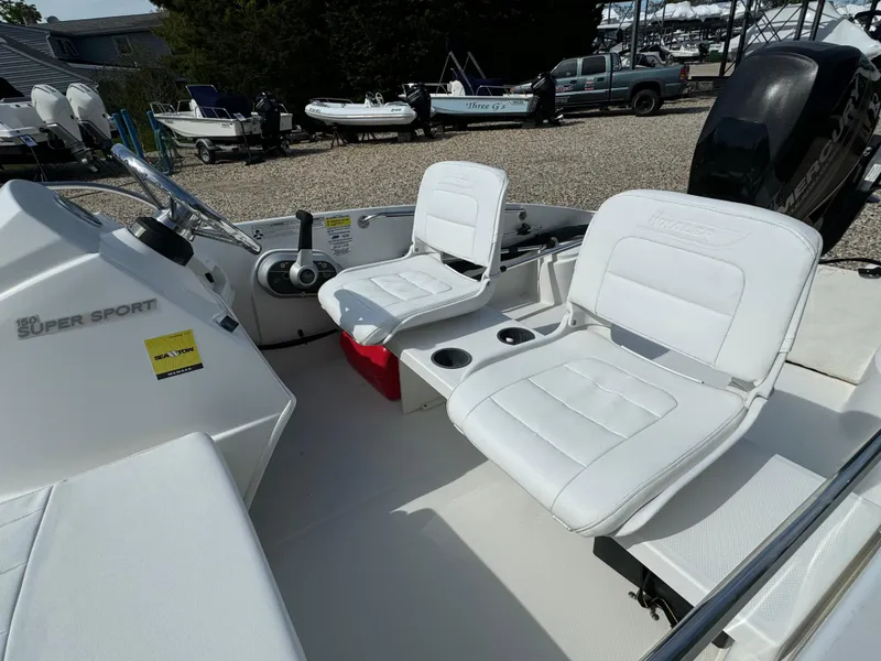 Slide: The Image of 2016 Boston Whaler 150 Super Sport boat interior with white seating and control console. - 4
