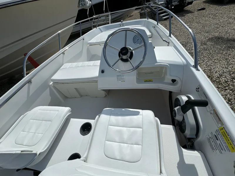Slide: The Image of 2016 Boston Whaler 150 Super Sport boat interior with white seating and steering wheel. - 5