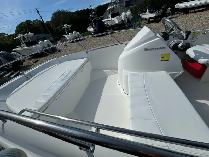 Slide: The Image of 2016 Boston Whaler 150 Super Sport boat interior with white seating and steering console. - 6
