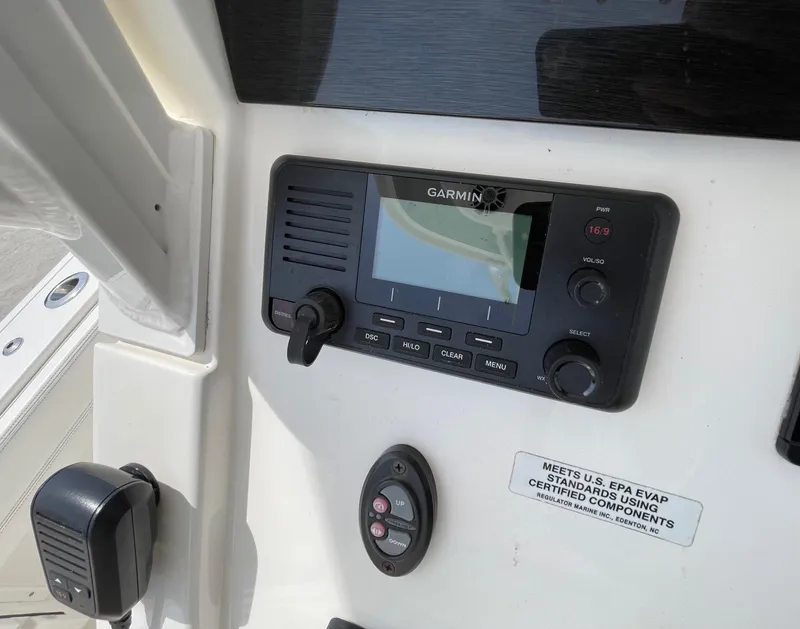 Slide: The Image of Garmin marine radio on 2021 Regulator 26XO boat dashboard, featuring control panel and certification label. - 16