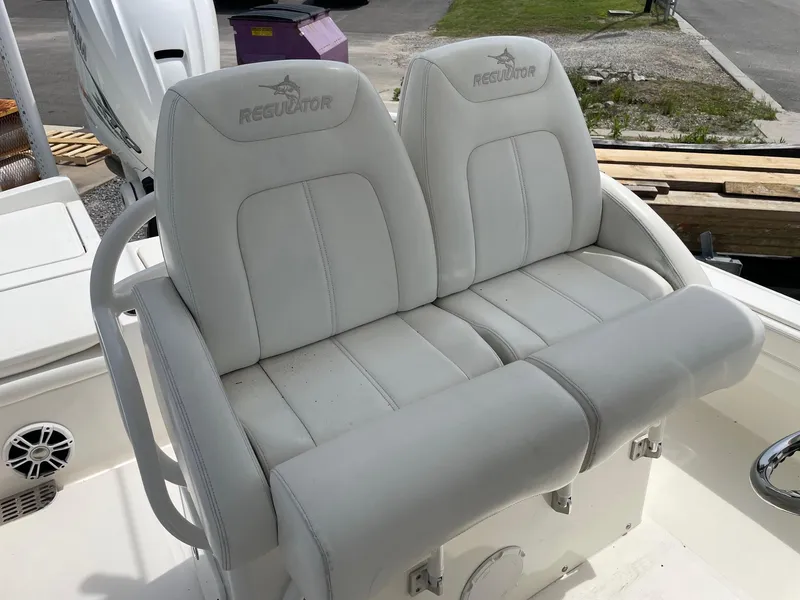 Slide: The Image of 2021 Regulator 26XO boat seats, white leather, dual seating, outdoor setting. - 19
