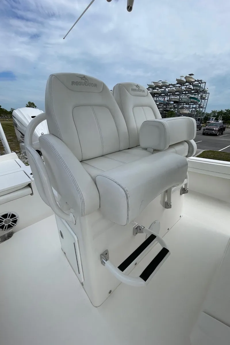 Slide: The Image of 2021 Regulator 26XO boat seats, white leather, dual seating, outdoor setting. - 20