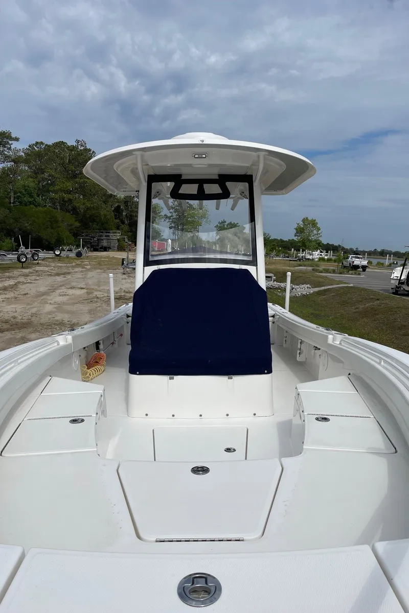 Slide: The Image of 2021 Regulator 26XO boat with blue seating, docked outdoors under a cloudy sky. - 21