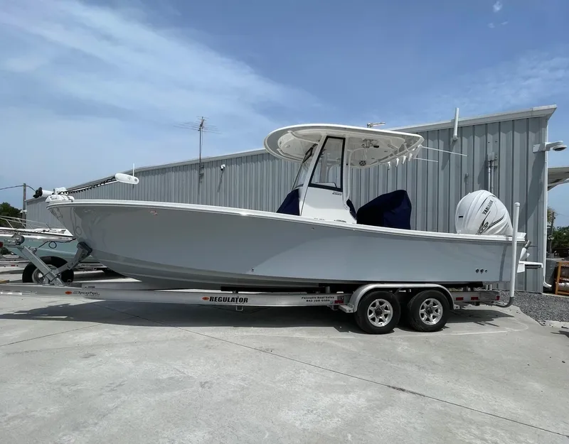 Slide: The Image of 2021 Regulator 26XO boat on trailer, parked outdoors near a metal building. - 3