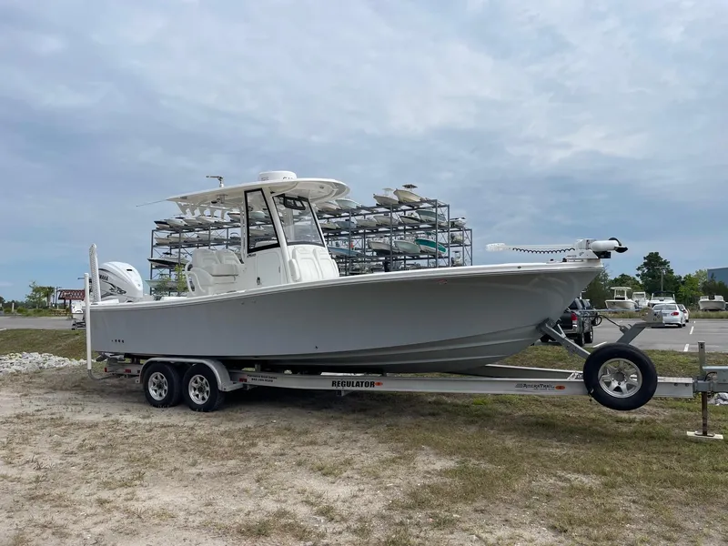 Slide: The Image of 2021 Regulator 26XO boat on trailer, parked outdoors under cloudy sky. - 6