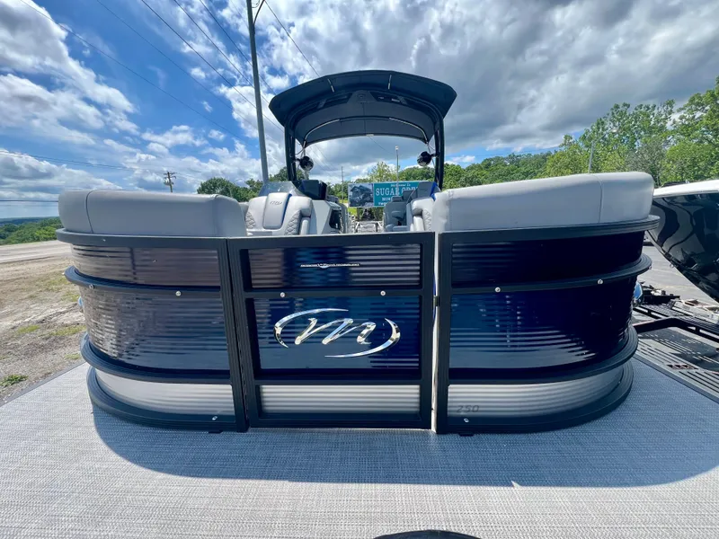 Slide: The Image of 2022 Manitou 25 LX SHP DE pontoon boat, rear view, under a partly cloudy sky. - 1