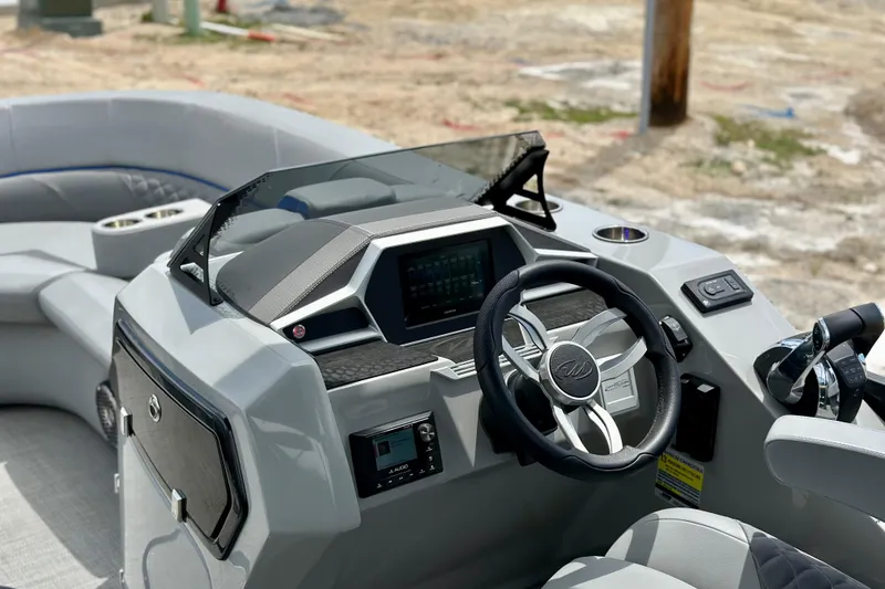 Slide: The Image of 2022 Manitou 25 LX SHP DE boat dashboard with steering wheel and controls. - 13