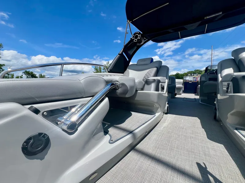 Slide: The Image of 2022 Manitou 25 LX SHP DE boat interior with sleek seating and modern design under a blue sky. - 18