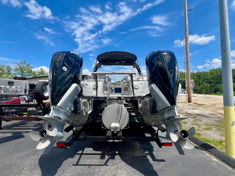 Slide: The Image of 2022 Manitou 25 LX SHP DE boat with dual outboard motors, parked under a clear blue sky. - 24