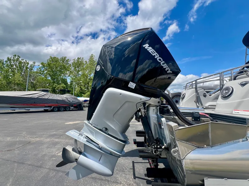 Slide: The Image of 2022 Manitou 25 LX SHP DE with Mercury outboard motor, parked outdoors under blue sky. - 27