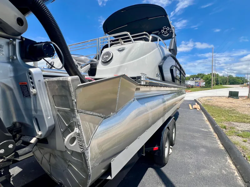 Slide: The Image of 2022 Manitou 25 LX SHP DE pontoon boat on trailer, sunny day, blue sky. - 30