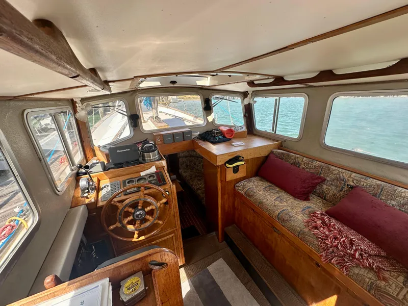 Slide: The Image of Interior of 1985 Fisher 34 Pilothouse Ketch with wooden helm and cozy seating. - 10