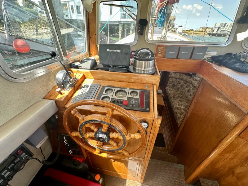 Slide: The Image of 1985 Fisher 34 Pilothouse Ketch interior with wooden steering wheel and navigation equipment. - 12