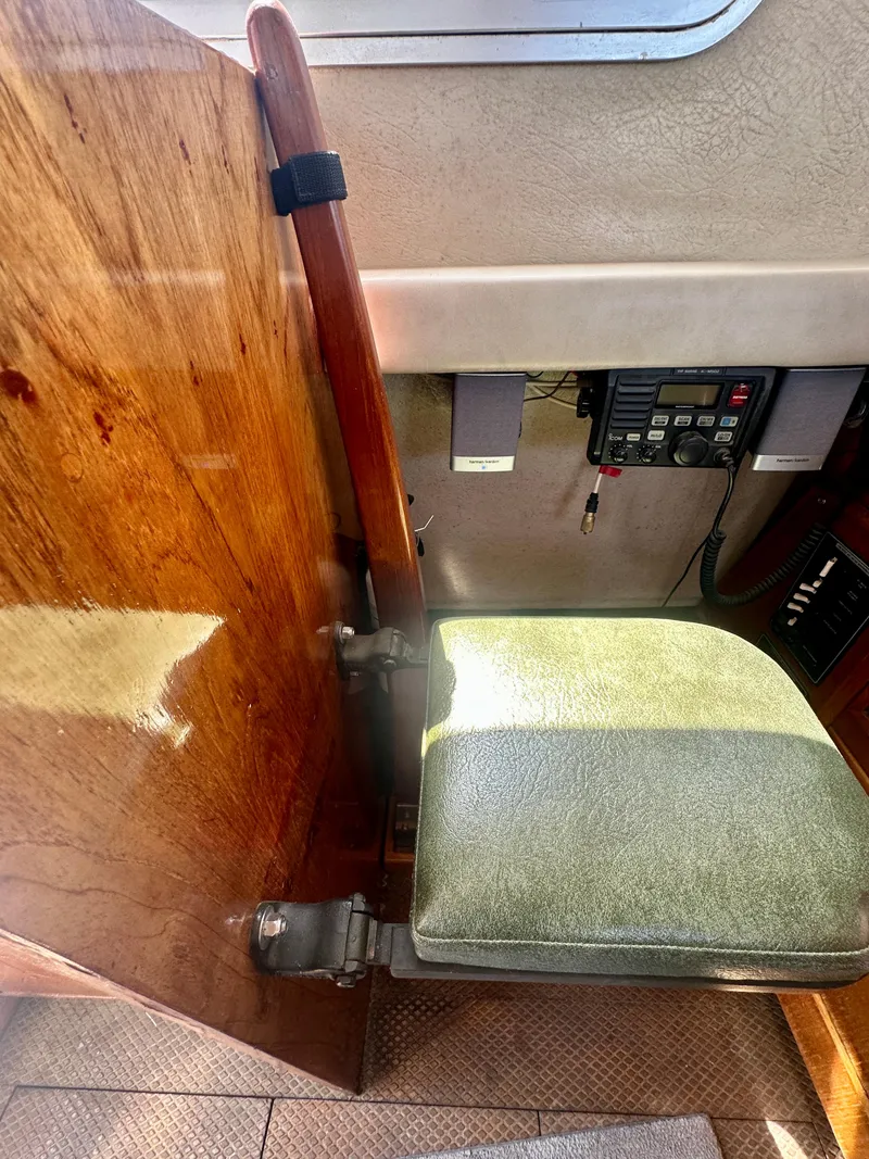 Slide: The Image of 1985 Fisher 34 Pilothouse Ketch interior with wooden paneling and cushioned seat. - 13