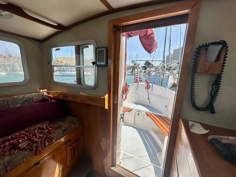 Slide: The Image of Interior view of 1985 Fisher 34 Pilothouse Ketch, showing cozy seating and marina outside. - 26