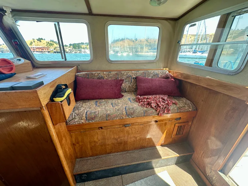 Slide: The Image of 1985 Fisher 34 Pilothouse Ketch interior with cushioned seating and scenic window views. - 27
