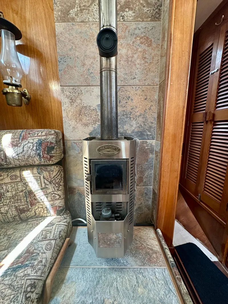 Slide: The Image of Wood stove inside 1985 Fisher 34 Pilothouse Ketch, with cozy seating and wooden interior. - 38