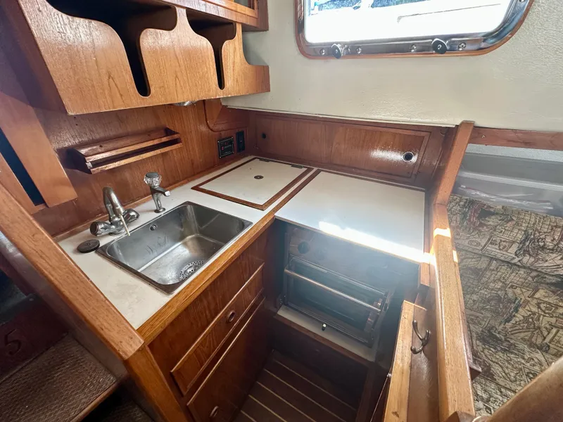 Slide: The Image of Compact galley in 1985 Fisher 34 Pilothouse Ketch with sink, stove, and wooden cabinetry. - 39
