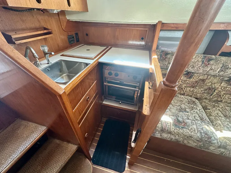Slide: The Image of 1985 Fisher 34 Pilothouse Ketch interior with kitchen, sink, stove, and seating area. - 40