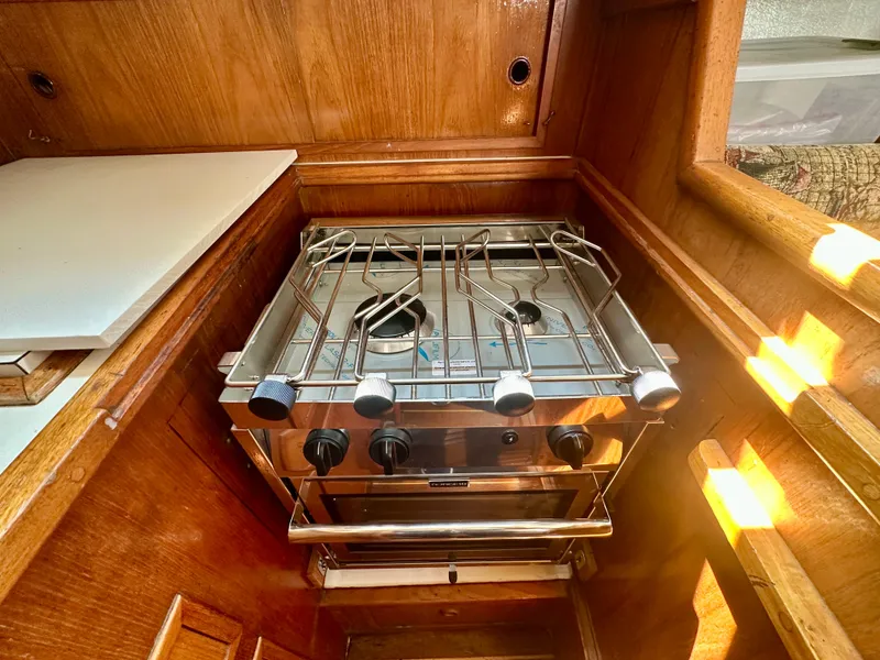 Slide: The Image of Compact kitchen stove in 1985 Fisher 34 Pilothouse Ketch, featuring wooden cabinetry. - 42