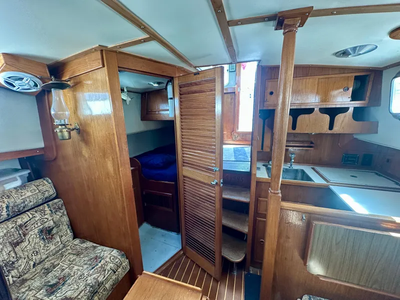 Slide: The Image of Interior of 1985 Fisher 34 Pilothouse Ketch, featuring wood paneling and compact living space. - 46