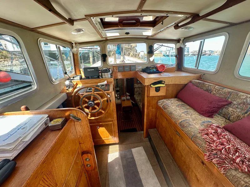 Slide: The Image of 1985 Fisher 34 Pilothouse Ketch interior with wooden helm, seating, and nautical decor. - 9