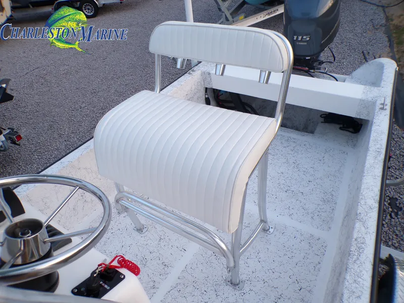 Slide: The Image of White cushioned seat on 2023 Panga 22 boat deck, featuring steering wheel and motor. - 7