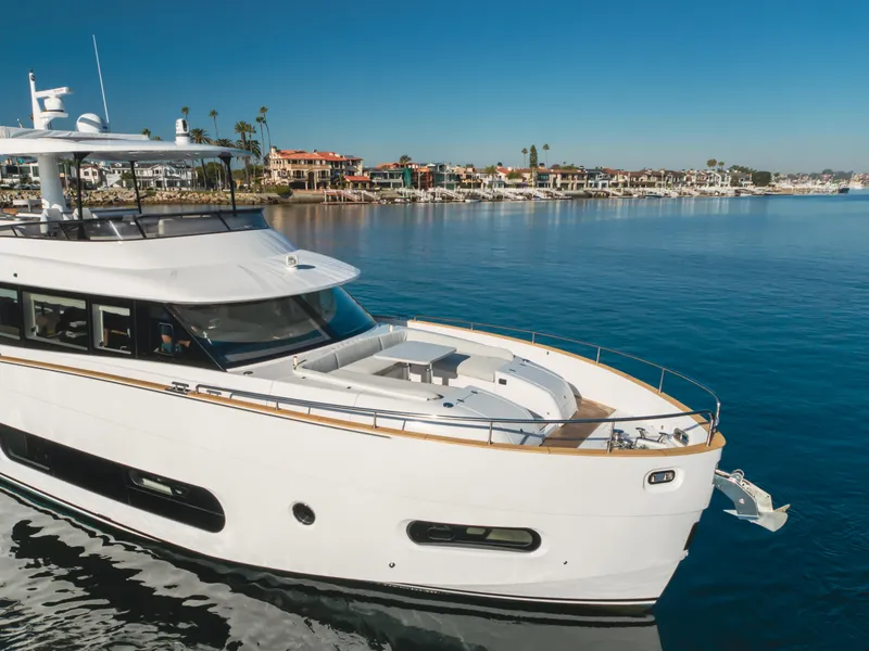 Slide: The Image of 2023 Azimut Magellano 66 yacht cruising near a coastal town under clear blue skies. - 2