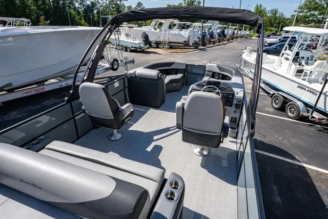 Slide: The Image of 2024 South Bay S224 UL 3.0 pontoon boat interior with seating and helm, parked in marina. - 21