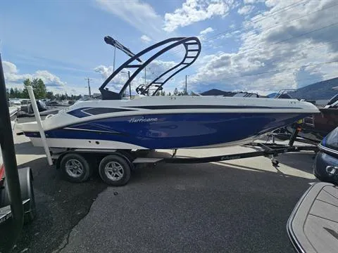 Slide: The Image of 2022 Hurricane SunDeck Sport 205 IO boat on trailer, blue and white design, parked outdoors. - 4