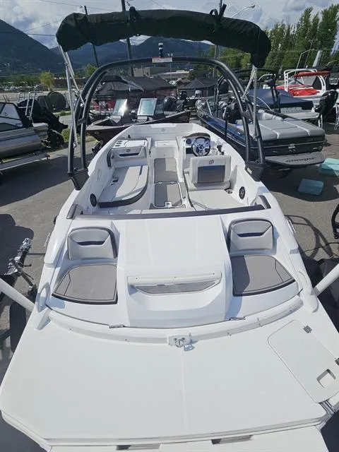 Slide: The Image of 2022 Hurricane SunDeck Sport 205 IO boat with seating, steering wheel, and canopy in a marina. - 5