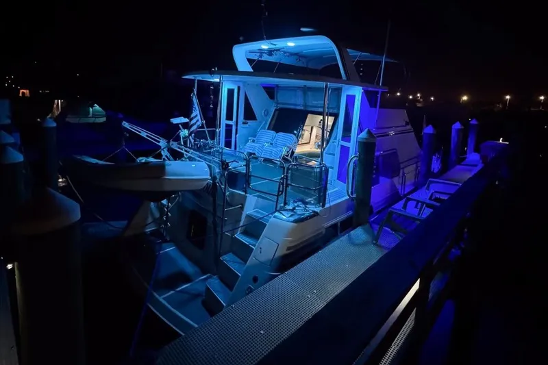 Slide: The Image of Illuminated 1994 President 445 Sundeck yacht docked at night with blue lighting. - 158