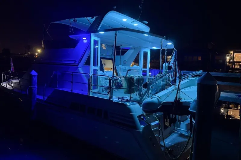 Slide: The Image of 1994 President 445 Sundeck yacht illuminated at night with blue lights. - 159